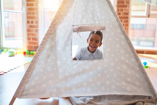Beautiful african american toddler playing inside tipi smiling at kindergarten