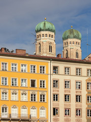 Fototapeta na wymiar Spires of Frauenkirche behind facades of houses at Marienplatz