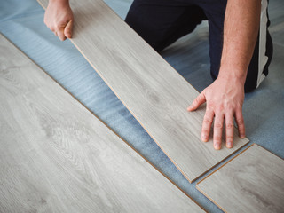 A man holds a laminate board in his hands. The repair process in the room