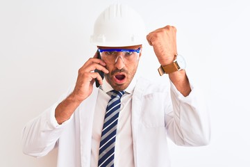 Young scientist man wearing safety helmet and calling using smartphone over isolated background annoyed and frustrated shouting with anger, crazy and yelling with raised hand, anger concept