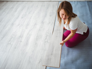 The repair process in the apartment. The girl performs the laying of the laminate