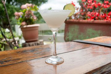Cup with drink called Margarita, served outdoors on wooden table, drink with alcohol.