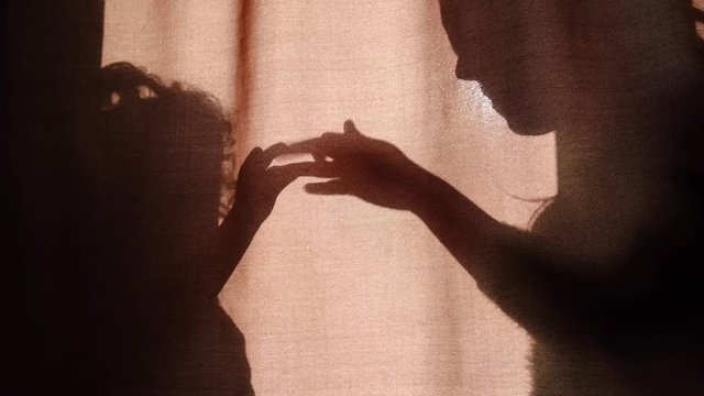 Silhouette of unrecognizable mother and child of primary school age telling stories using shadow presents talking dog's heads when sitting behind the curtains at home on a sunny day  - Powered by Adobe