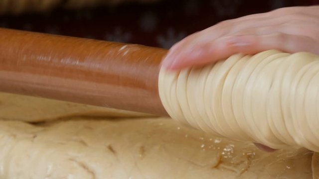 Female hands wrap the sticks of dough on a wooden stick. National Czech trdelnik sweet delicacy that is prepared on the street.Traditional Czech and Hungarian baking sweet bakery.