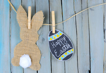 Bunny shape in burlap with a cotton swab tail hanging from twine by clothespins. Chalkboard hand...