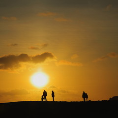 Fototapeta premium Silhouettes of people walk on horizon at sunset