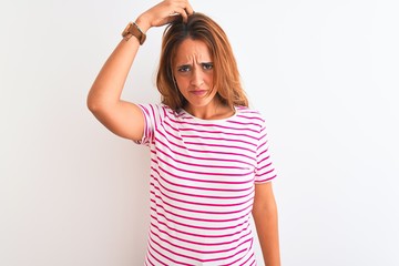Young redhead woman wearing striped casual t-shirt stading over white isolated background confuse and wonder about question. Uncertain with doubt, thinking with hand on head. Pensive concept.
