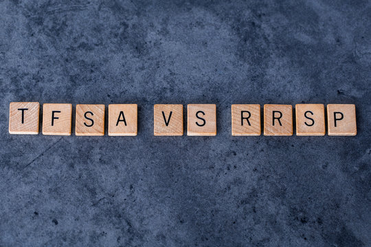 "TFSA vs RRSP" spelled out in wooden letter tiles on a dark rough background
