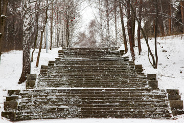 Stone steps of an old staircase in a winter park. A quiet, uninhabited place in the forest. Snow covered stairs. Background.