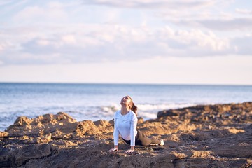 Young beautiful sportwoman practicing yoga. Coach teaching upward-facing dog pose at the beach