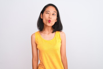 Fototapeta premium Young chinese woman wearing yellow casual t-shirt standing over isolated white background making fish face with lips, crazy and comical gesture. Funny expression.