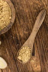 Some Ginger Powder on a vintage wooden table (selective focus; close-up shot)