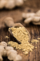 Some Ginger Powder on a vintage wooden table (selective focus; close-up shot)