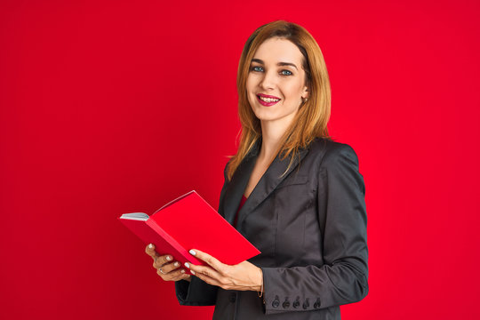 Young beautiful redhead businesswoman wearing suit reading book