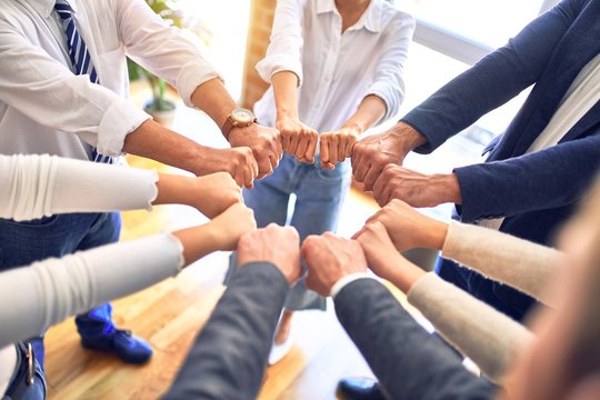 Group of business workers standing bumping fists at the office