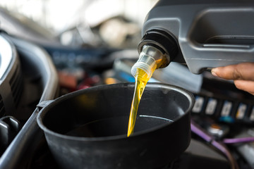 Car mechanic fills a fresh lubricant engine oil