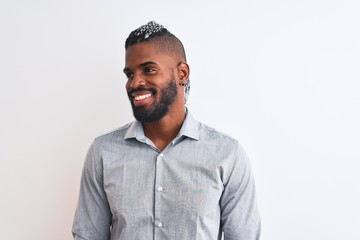 Obraz premium African american businessman with braids standing over isolated white background looking away to side with smile on face, natural expression. Laughing confident.