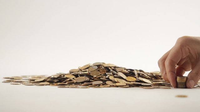 The concept of money. Columns of gold coins in the form of skyscrapers or Stonehenge. Close-up hands make up stacks of coins. Smoke. Garland.
