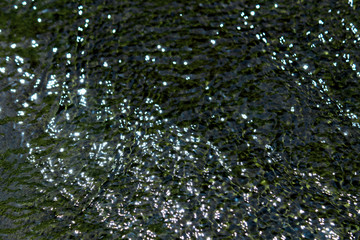 Closeup photo as a background material of pure water flow reflecting glitter and sunlight