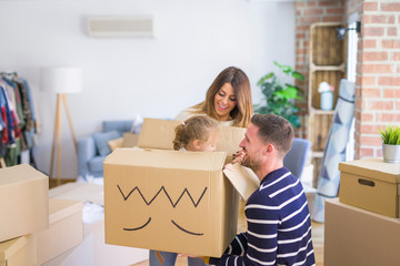 Beautiful famiily, kid playing with his parents riding fanny cardboard box at new home