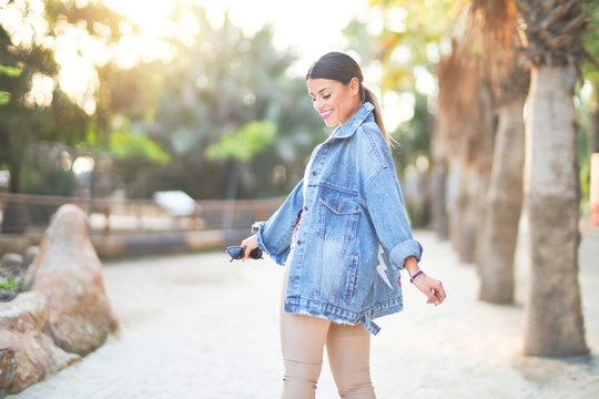 Young beautiful woman wearing denim jacket smiling happy and confident. Standing with smile on face at the town park