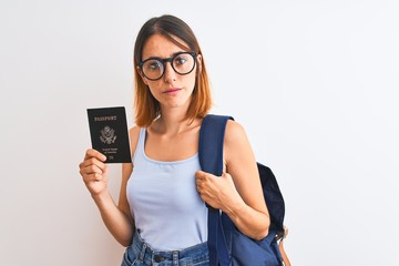 Fototapeta premium Beautiful redhead student woman wearing backpack and holding passport of united states with a confident expression on smart face thinking serious