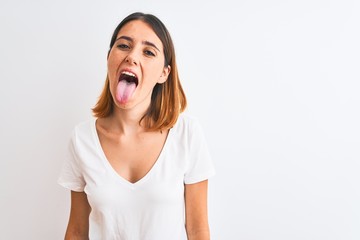 Beautiful redhead woman wearing casual white t-shirt over isolated background sticking tongue out...