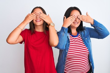 Young beautiful women wearing casual clothes standing over isolated white background covering eyes with hands smiling cheerful and funny. Blind concept.
