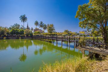 Fototapeta premium Background of Wat Traphang Thong, which is located in the middle of the water and has a wooden bridge, which is used to organize ceremonies (Loi Krathong, New Year) in Sukhothai province, Thailand.