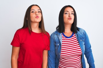 Young beautiful women wearing casual clothes standing over isolated white background looking at the camera blowing a kiss on air being lovely and sexy. Love expression.