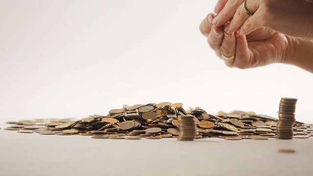 The concept of money. Columns of gold coins in the form of skyscrapers or Stonehenge. Close-up hands make up stacks of coins. Smoke. Garland.