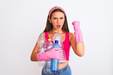 Beautiful girl wearing cleaner gloves recycling plastic bottles over isolated white background annoyed and frustrated shouting with anger, crazy and yelling with raised hand, anger concept