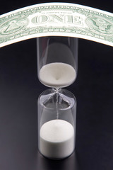 Dollar bills lie near the hourglass. Time is money. The salary. Business solutions in time....