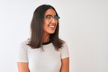 Chinese woman wearing casual t-shirt and glasses standing over isolated white background looking away to side with smile on face, natural expression. Laughing confident.