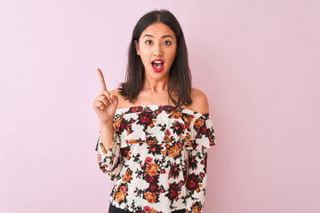 Young chinese woman wearing floral t-shirt standing over isolated pink background pointing finger up with successful idea. Exited and happy. Number one.