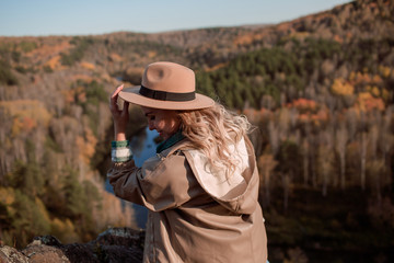 Young blonde in hat walking on top of mountain in autumn