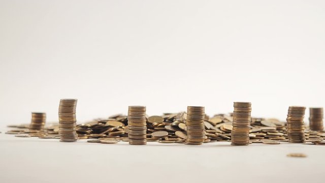 The concept of money. Columns of gold coins in the form of skyscrapers or Stonehenge. Close-up hands make up stacks of coins. Smoke. Garland.