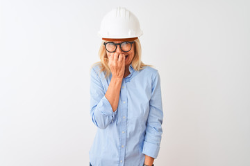 Middle age architect woman wearing glasses and helmet over isolated white background looking stressed and nervous with hands on mouth biting nails. Anxiety problem.