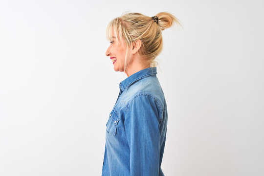 Middle age woman wearing casual denim shirt standing over isolated white background looking to side, relax profile pose with natural face with confident smile.