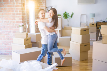 Young beautiful couple hugging at new home around cardboard boxes