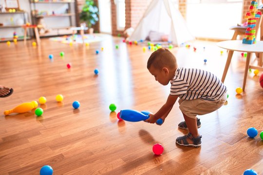 Beautiful toddler boy playing bowling at kindergarten