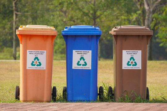 Different colors of recycle bin at public park.