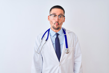 Young doctor man wearing stethoscope over isolated background making fish face with lips, crazy and comical gesture. Funny expression.