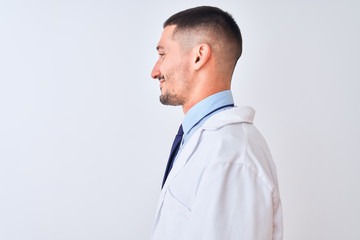 Young doctor man wearing white coat over isolated background looking to side, relax profile pose with natural face with confident smile.