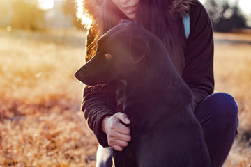 A woman with her adorable black dog  in a field in the morning