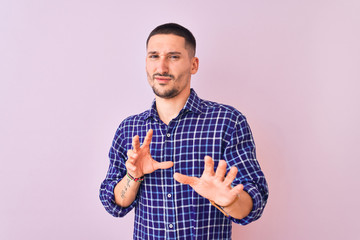 Young handsome man standing over isolated background disgusted expression, displeased and fearful doing disgust face because aversion reaction. With hands raised. Annoying concept.