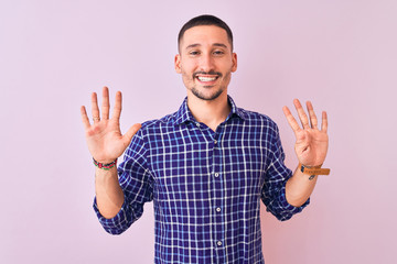 Young handsome man standing over isolated background showing and pointing up with fingers number...