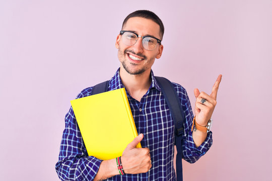 Young handsome student man holding a book over isolated background very happy pointing with hand and finger to the side