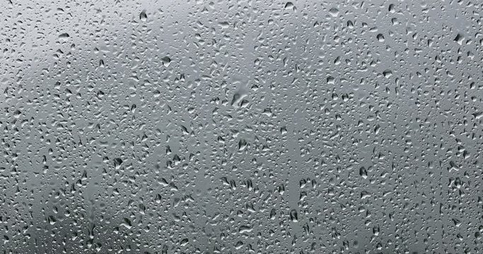 Rainy window on a cloudy day. Raindrops on a wet glass surface background.