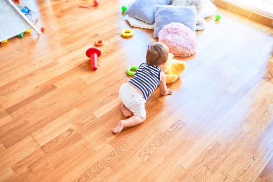 Adorable toddler crawling around lots of toys at kindergarten